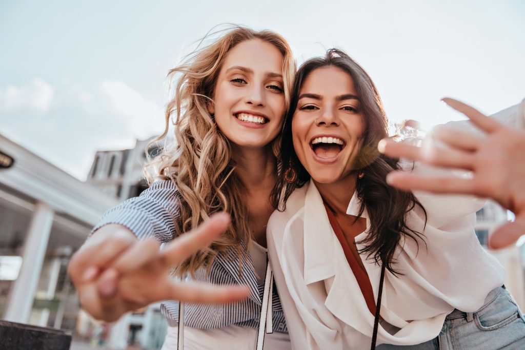 two women smiling and making peace signs